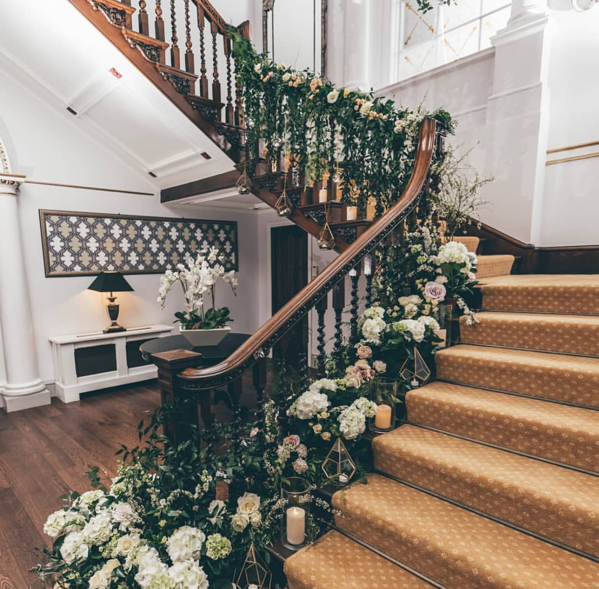 Grand staircase dressed with lush greenery, ivory hydrangeas and candle lanterns