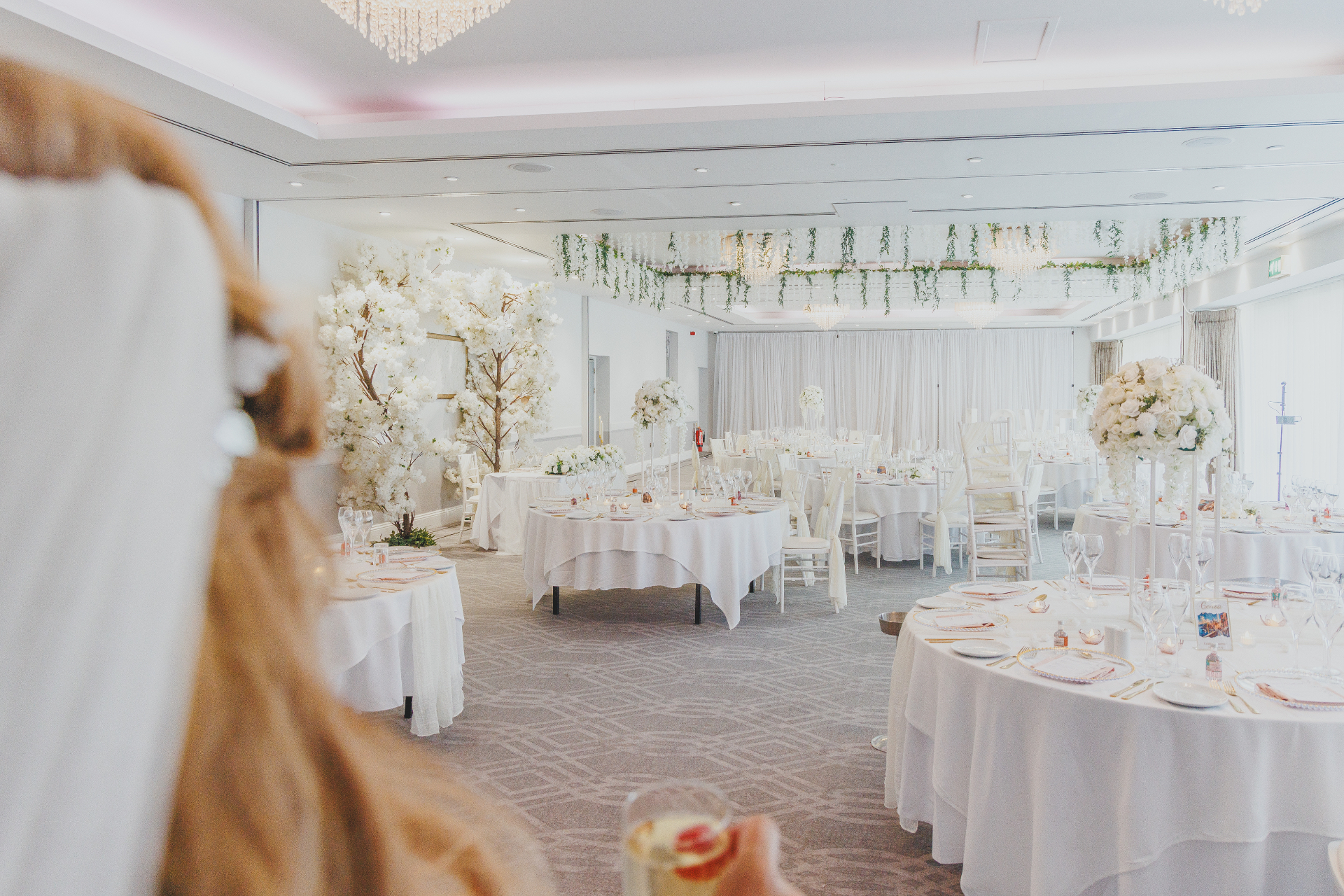All-white reception room with hanging florals and elegant round tables