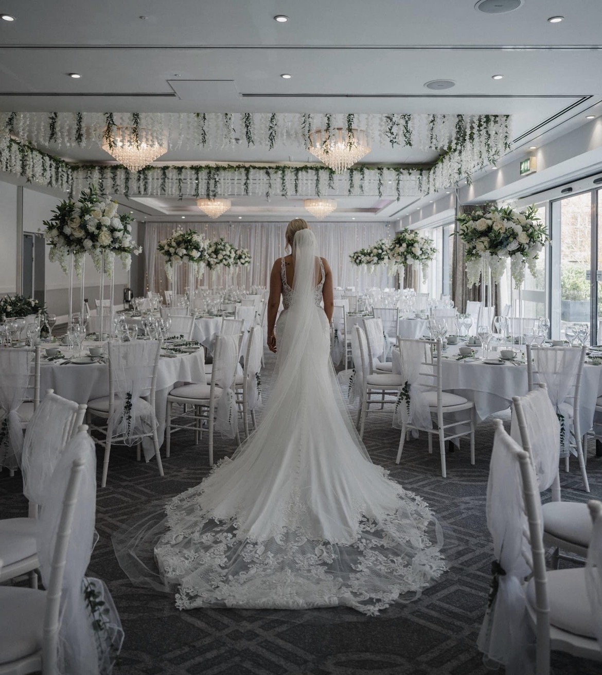 Bride in a luxury ballroom styled with floral towers and chiavari chairs