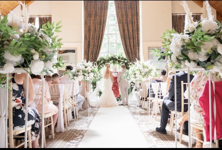 Ceremony aisle lined with tall white arrangements leading to the couple